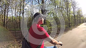 Handsome young man cycling through sunny park on summer`s day. Action camera Slow Motion