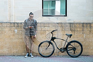 Handsome Young Man Cyclist Standing Next To Bike And His Looking At Smartphone. Street Lifestyle Urban Everyday Concept