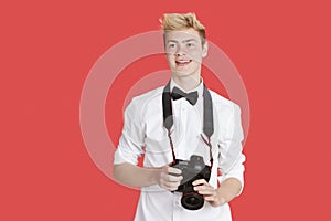 Handsome young man with digital camera over red background