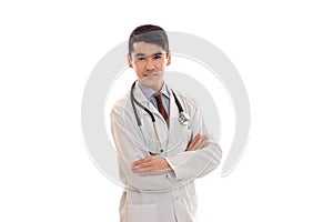Handsome young man doctor in uniform with stethoscop on his neck looking and posing on camera with crossed hands