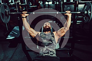 Handsome young man doing bench press workout in gym