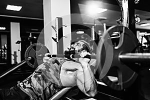 Handsome young man doing bench press workout in gym