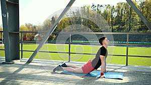 Handsome Young Man Doing Hamstring Stretch Exercise On Top Of A Mat At Stadium. Feet Lie On The Carpet Emphasis On The