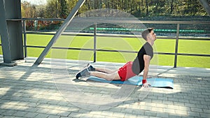 Handsome Young Man Doing Hamstring Stretch Exercise On Top Of A Mat At Stadium. Feet Lie On The Carpet Emphasis On The