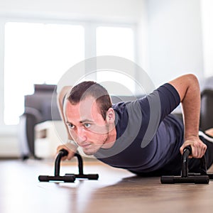 Handsome young man doing push-up at home