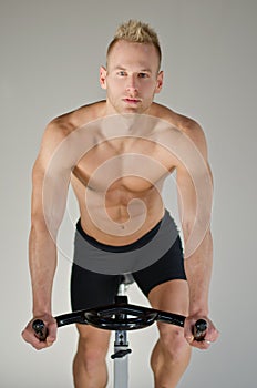 Handsome young man doing spinning on bike