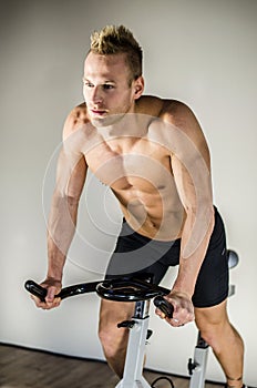 Handsome young man doing spinning on bike