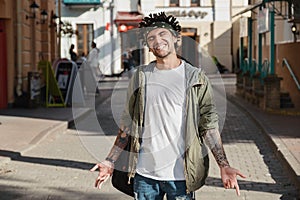 Handsome young man with dreadlocks hairstyle and head scarf, gangsta rap singer, rapper in city street. Afroamerican underground