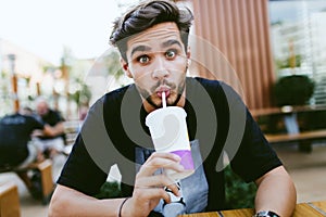 Handsome young man drinking refreshment at outdoor bar.