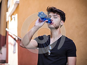 Handsome young man drinking water from bottle