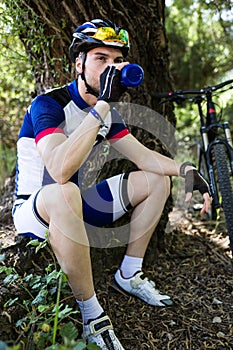 Handsome young man drinking water after cycling in the mountain. photo