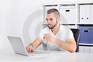 Handsome young man drinking water from a glass