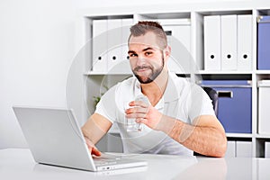 Handsome young man drinking water from a glass