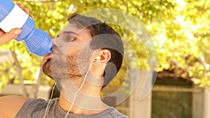 Handsome young man drinking water during jogging