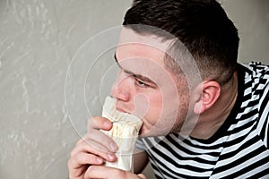 Handsome Young Man Eating Kebab. Hungry Man eating fast food indoors