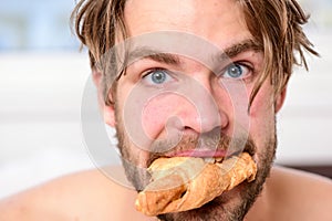 Handsome young man enjoying his morning cup of coffee laying in bed hotel room happy smiling. Handsome man drinking