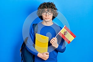 Handsome young man exchange student holding spanish flag depressed and worry for distress, crying angry and afraid