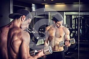 Handsome young man exercising biceps in gym