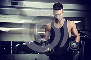 Handsome young man exercising biceps in gym