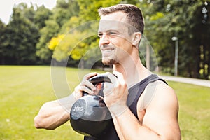 Handsome young man exercising using kettle bell