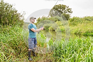 Handsome young man with a fishing rod on the river bank