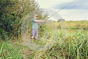 Handsome young man with a fishing rod on the river bank