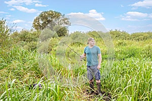 Handsome young man with a fishing rod on the river bank