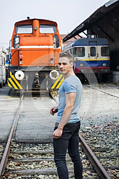 Handsome young man in front of old train, looking away