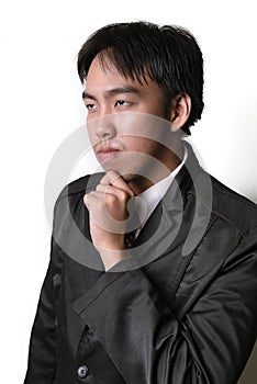 Handsome young man in full suit adjusting his necktie and looking at camera while standing against white background.