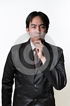 Handsome young man in full suit adjusting his necktie and looking at camera while standing against white background.