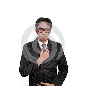 Handsome young man in full suit adjusting his necktie and looking at camera while standing against white background.