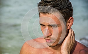 Handsome young man getting out of water with wet hair