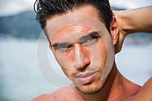 Handsome young man getting out of water with wet hair