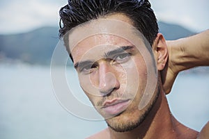 Handsome young man getting out of water with wet hair