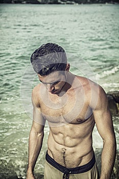 Handsome young man getting out of water with wet hair