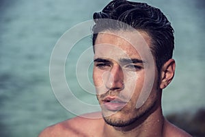 Handsome young man getting out of water with wet hair