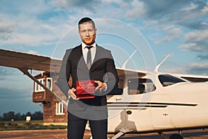 Handsome young man with gift box standing at airdrome