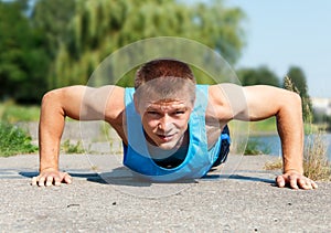 Handsome young man in good shape doing push-up while outdoor tra