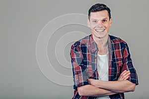 Happy young man. Portrait of handsome young man keeping arms crossed and smiling