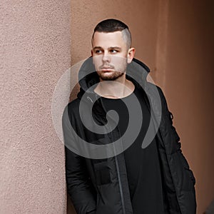 Handsome young man with a hairdo in a stylish black warm jacket