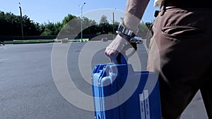 Handsome young man handcuffed to small blue bulletproof protected case get out of white modern car walk away action shot