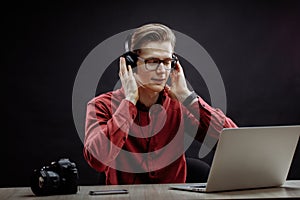 Handsome young man in headphones sitting in front of laptop