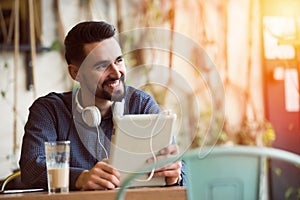 Handsome Young Man With Headphones using Tablet in Coffee Shop