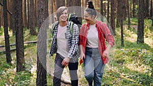 Handsome young man is hiking with his friend cheerful young woman talking and laughing touching trees and enjoying