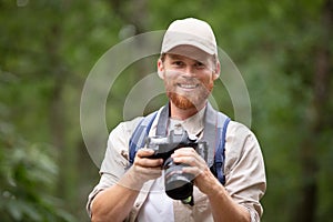 handsome young man hiking in mountain valley with dslr camera