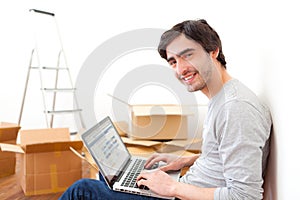 Handsome young man in his new flat using laptop