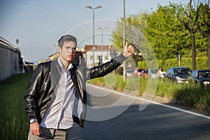 Handsome young man, hitchhiker waiting on roadside