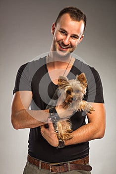 Handsome young man holding a yorkshire terrier dog