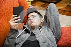 Handsome young man at home reading with ebook