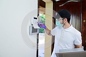 Handsome young man installing anti burglary alarm at a client house with a surgical mask and gloves COVID19 coronavirus